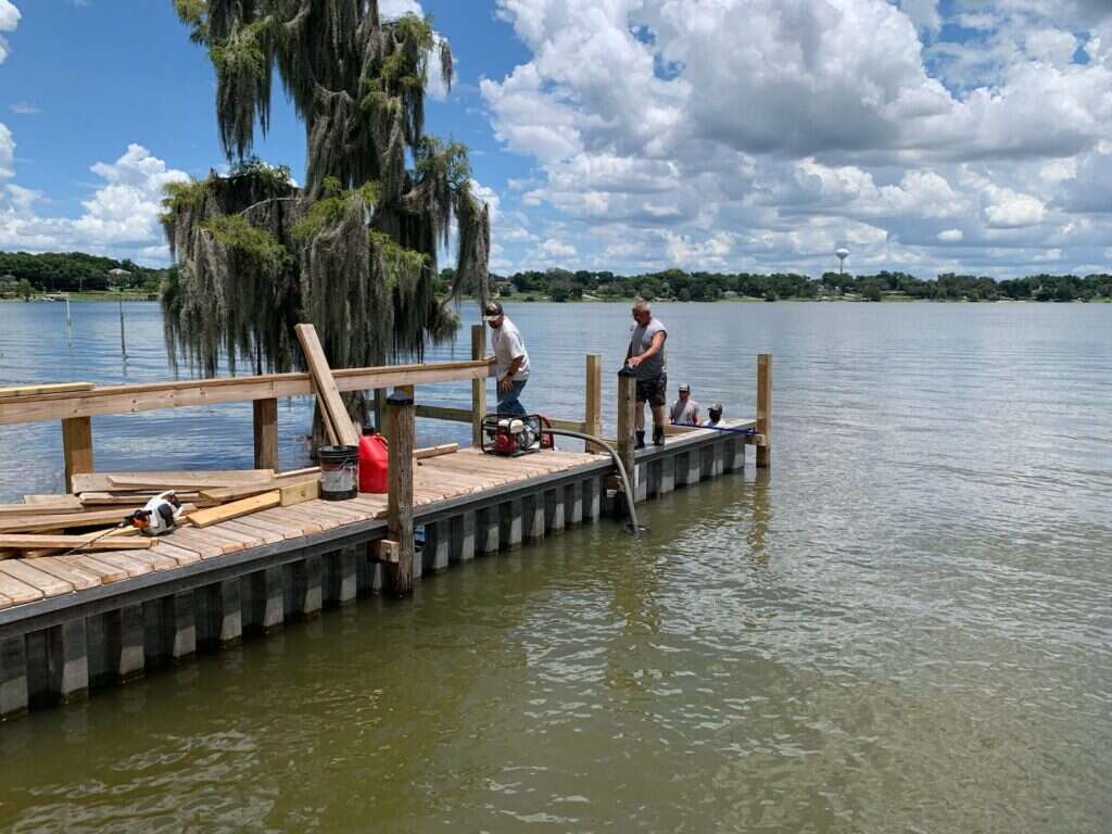 District crew rebuilding a dock beneath cypress trees
